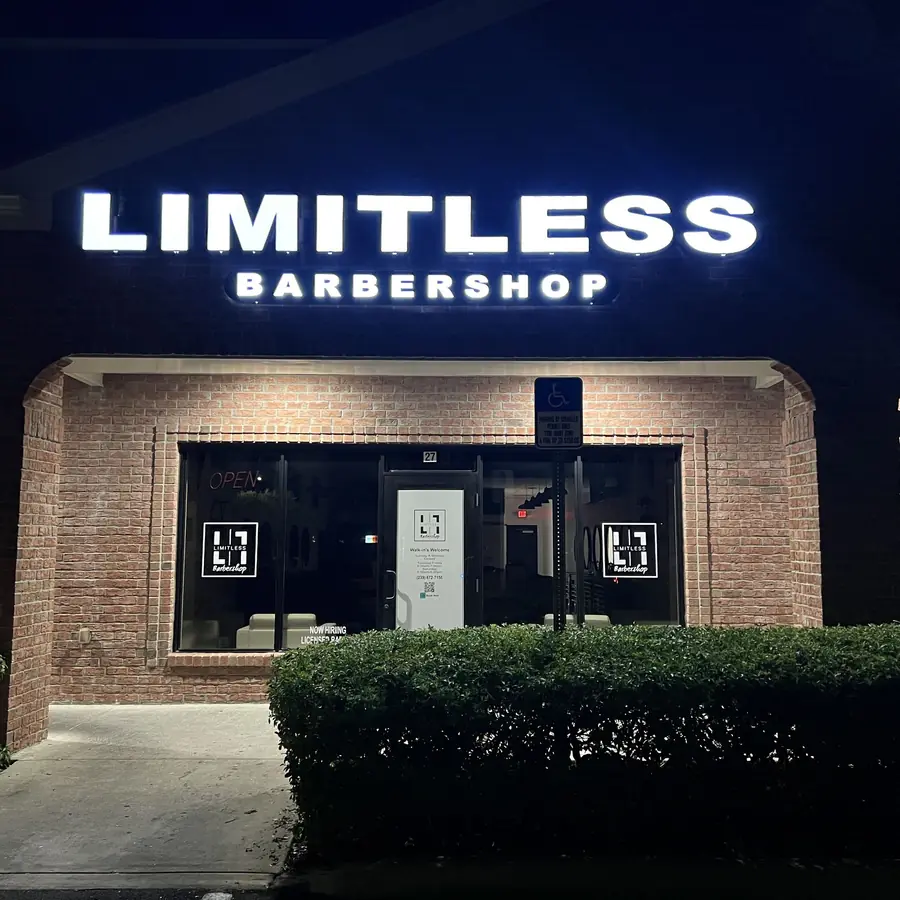 The Limitless Barbershop storefront at night with the lit sign